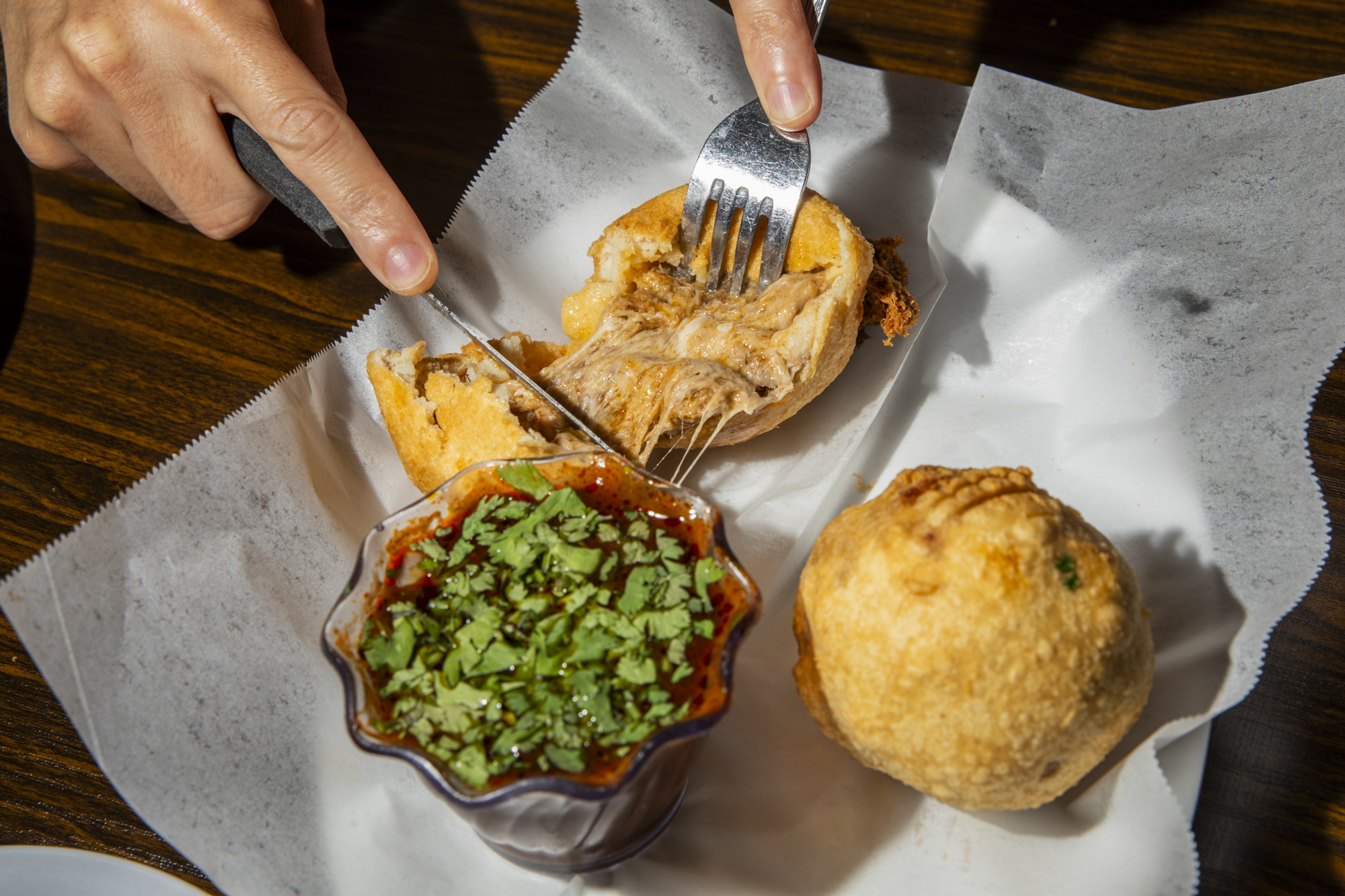 A fork and knife cut into a filled fried-looking ball.