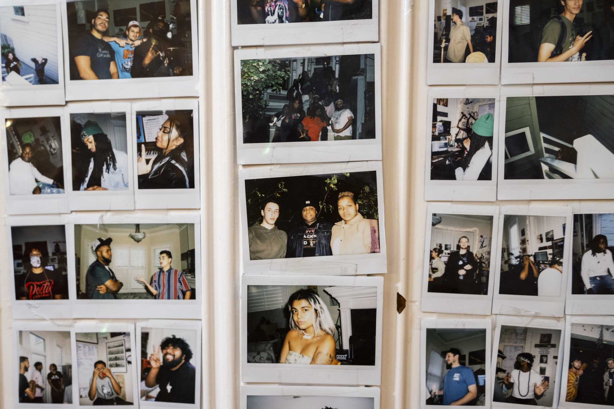 A collage of polaroid-type photos of people hand on a wall indoors.
