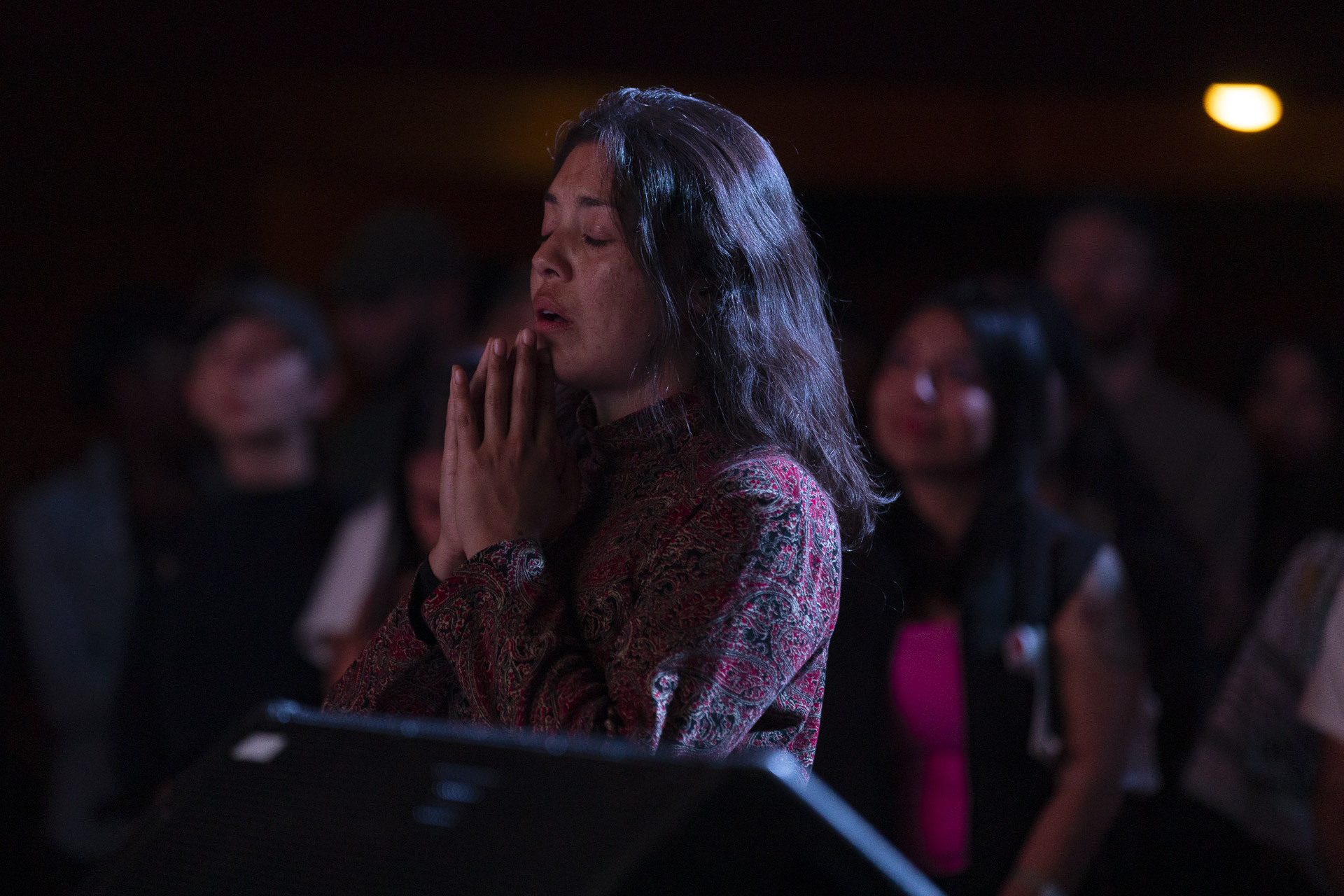 A woman in the audience closes her eyes while listening to a concert.