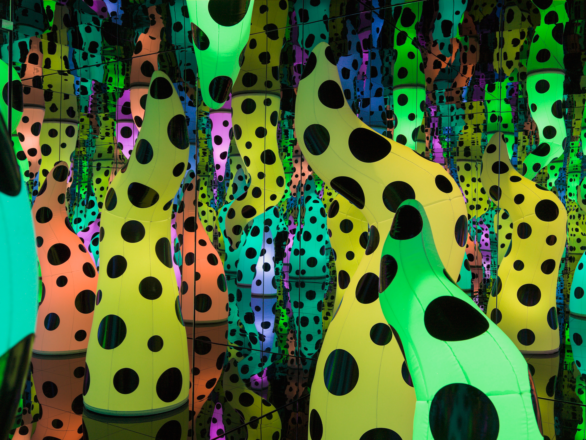 Mirrored room filled with inflated colorful tentacle shapes covered in black polka dots