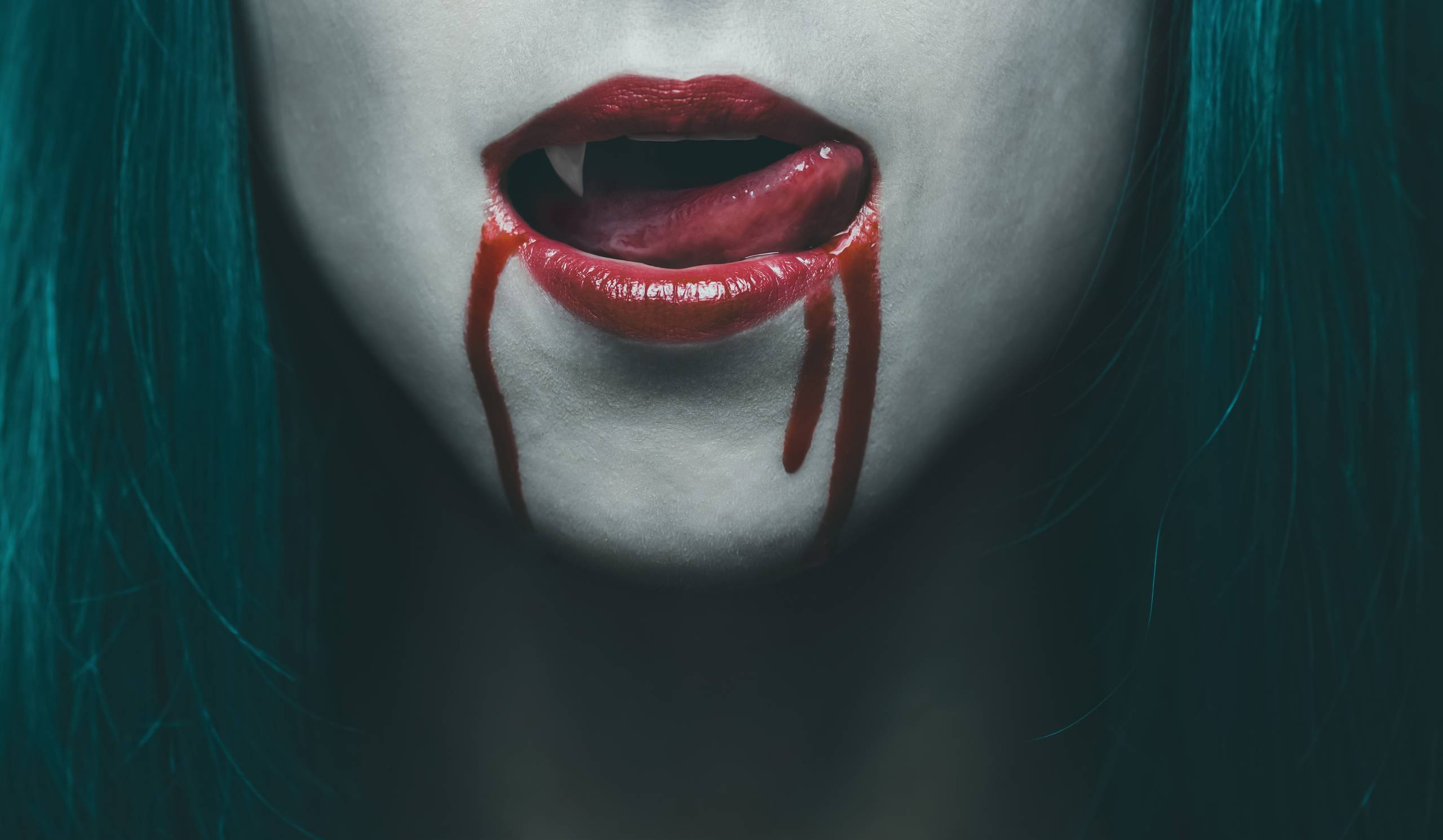 Female, red vampire lips with dripping blood, viewed in close-up.