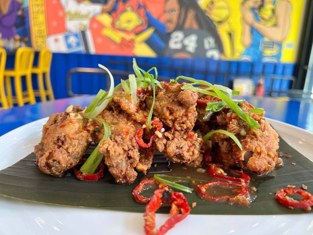 A plate of fried chicken wings garnished with red chilies and green onions.