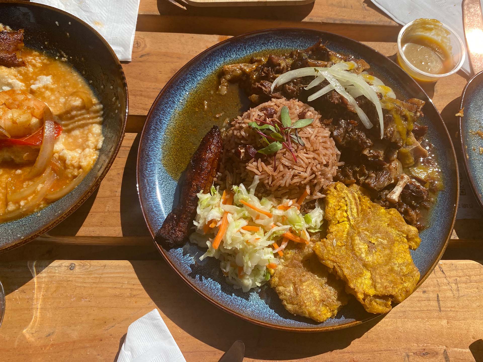 A plate of Haitian-style braised oxtails, served with a mound of rice and peas, tostones and pikliz.