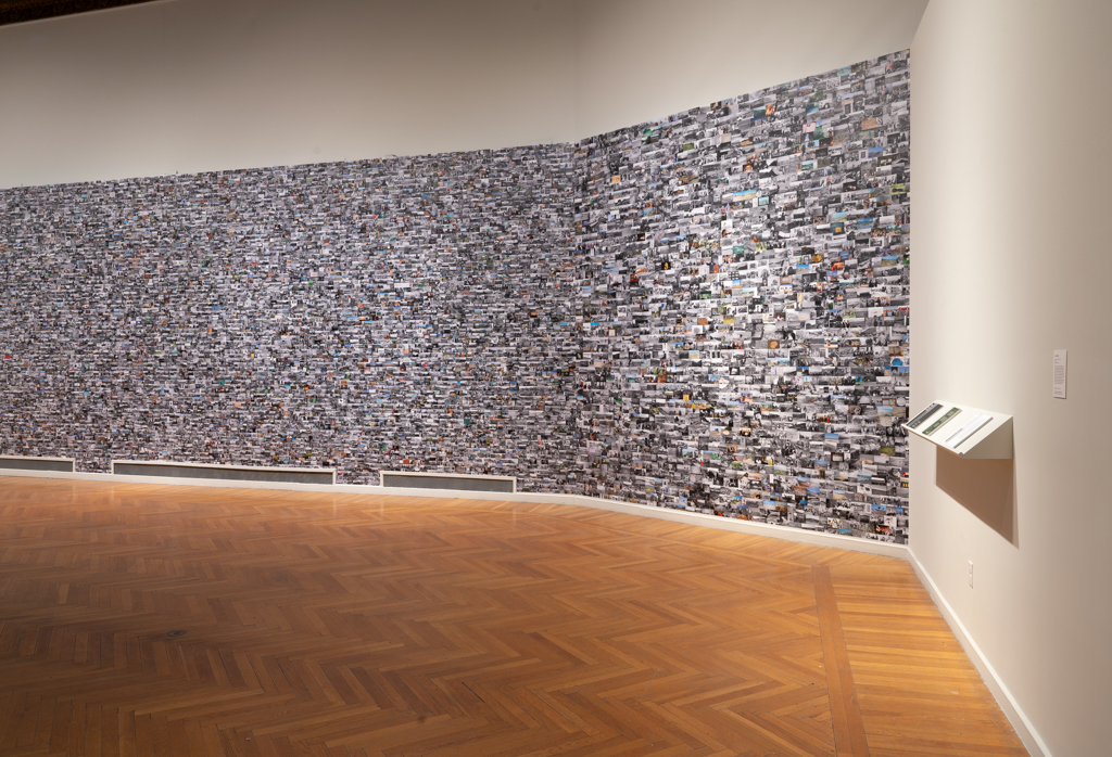 Gallery wall covered with thousands of small images as wallpaper, shelf with books at right