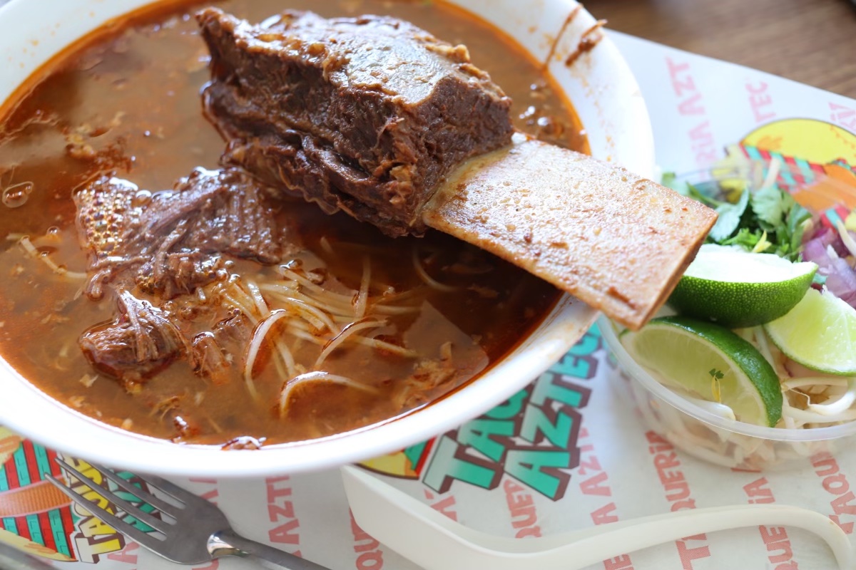 a bone-in slab of Mexican birria is served in a giant bowl of Vietnamese pho