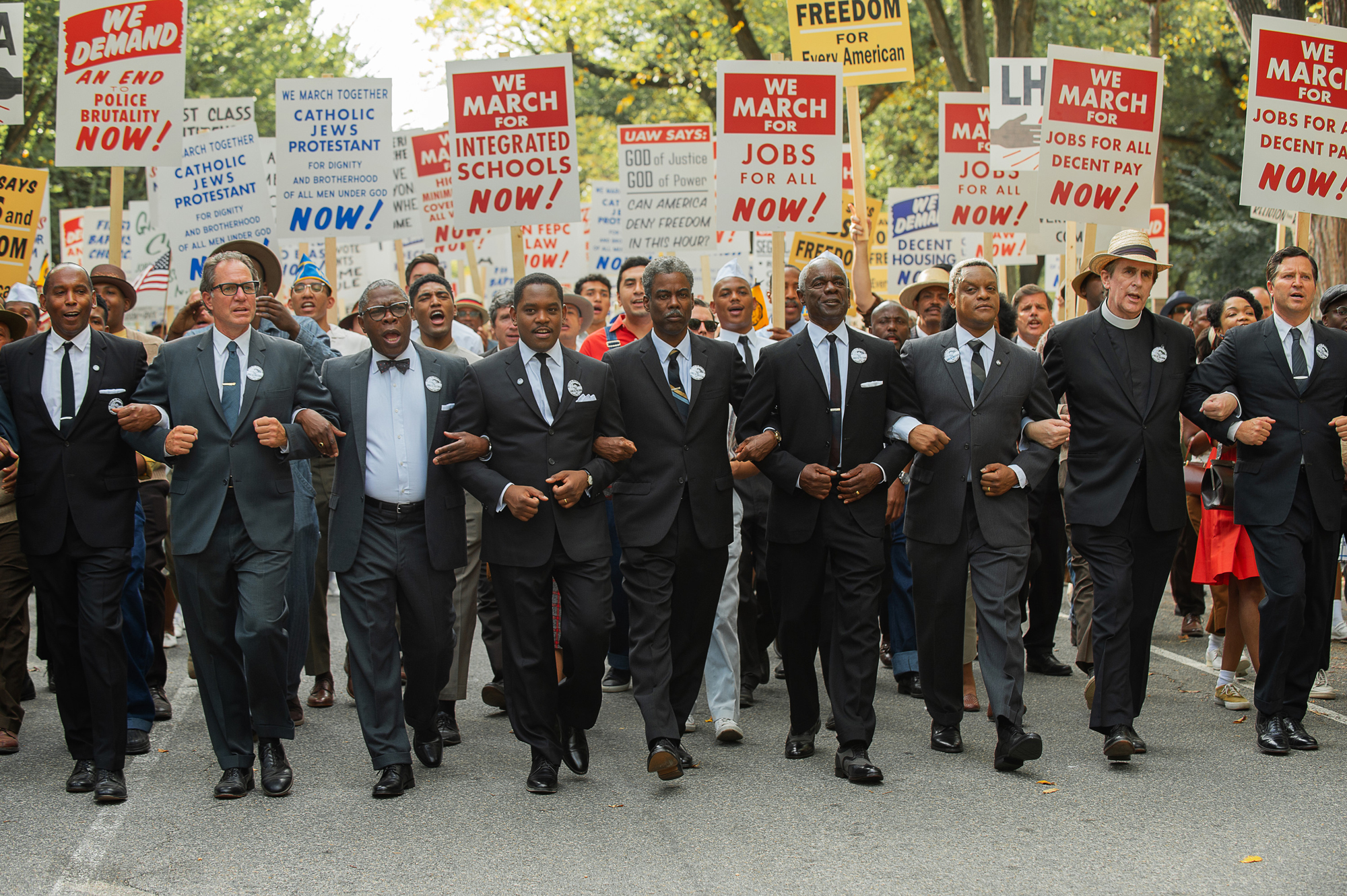 A group of men march arm in arm with posters for civil rights and integration