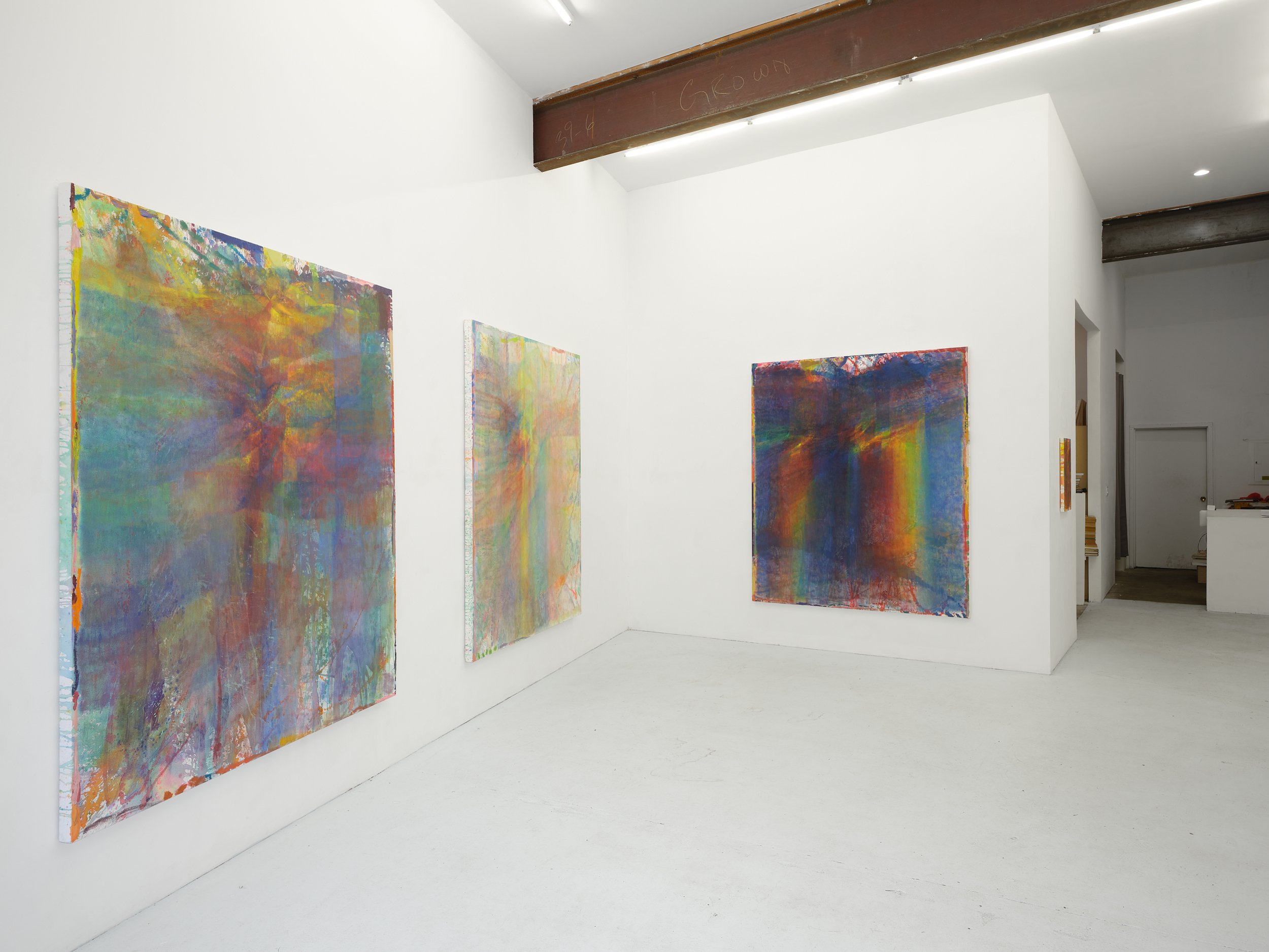 Three large rainbow-hued abstract paintings in white-walled gallery space