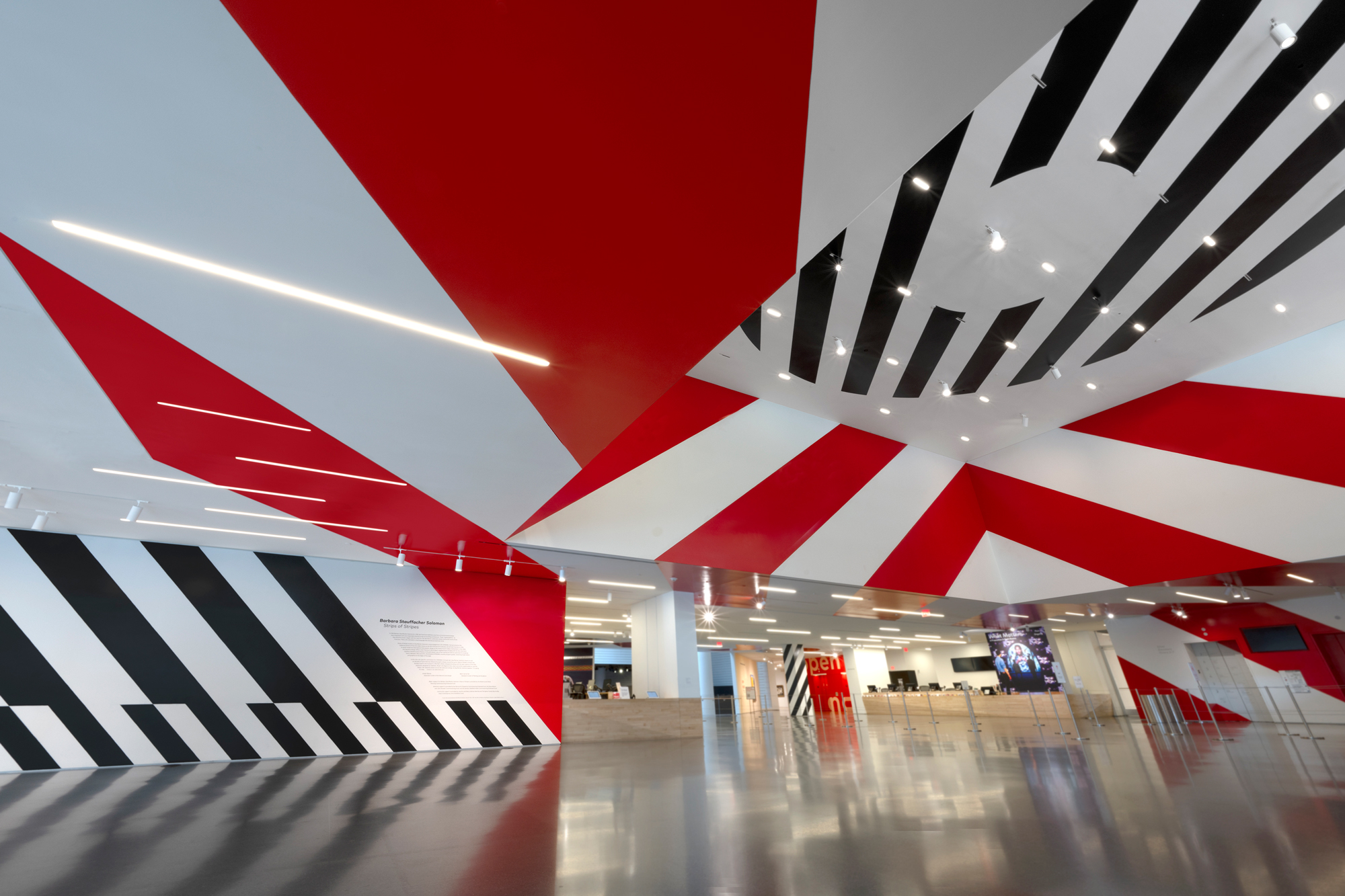 Red and black stripes painted on white walls and ceilings of lobby space
