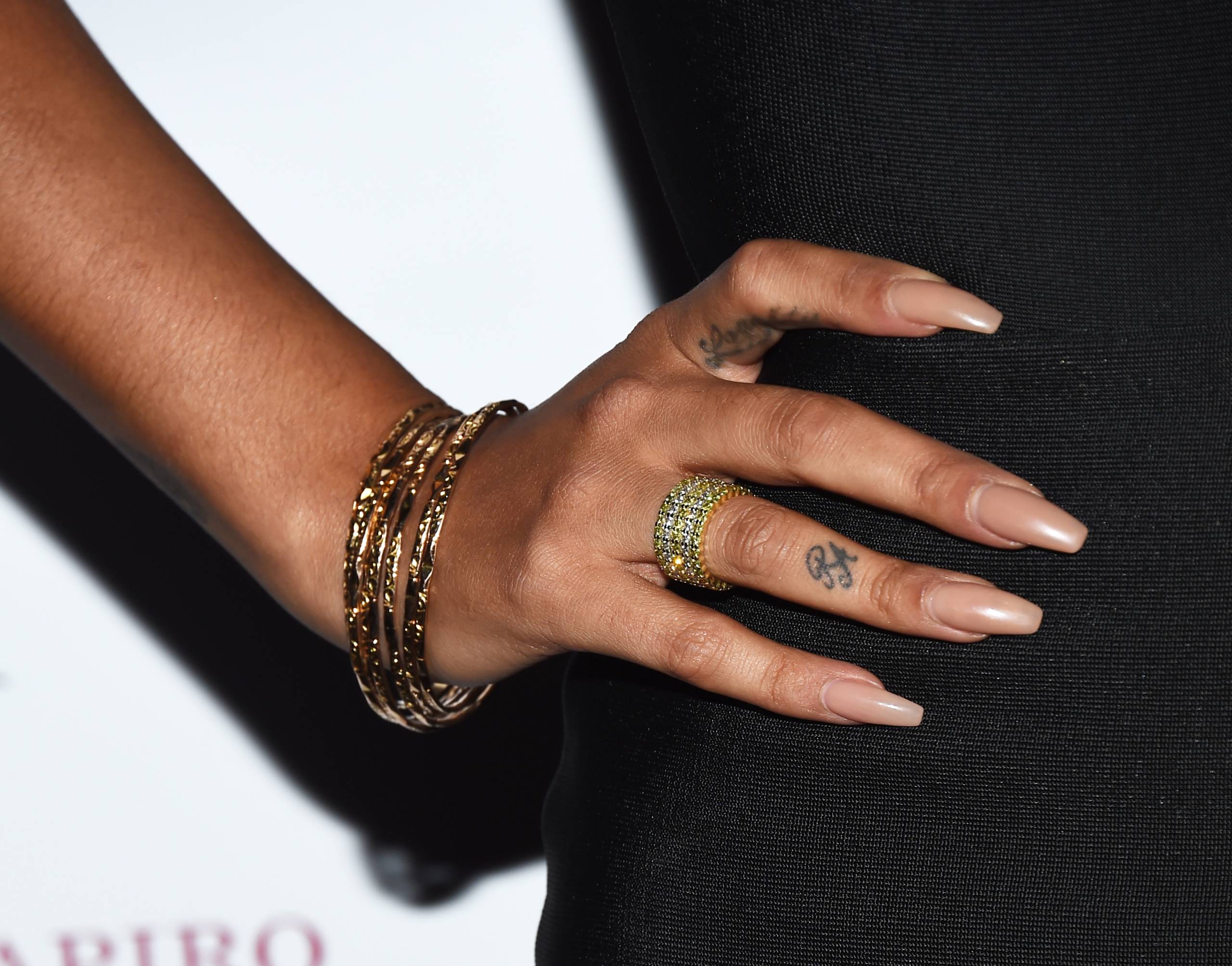 Close up of a manicured hand with bracelets and ring, placed on a hip.
