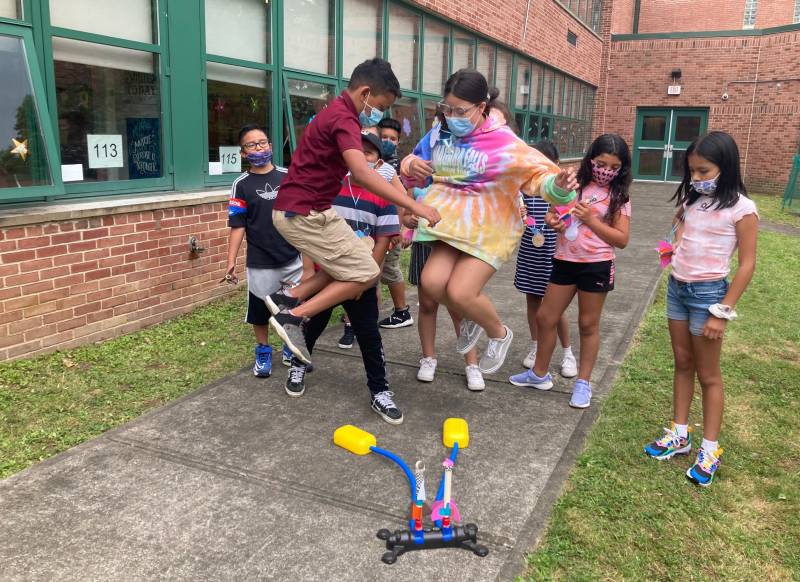 Students jump on pump to propel their rockets into the air