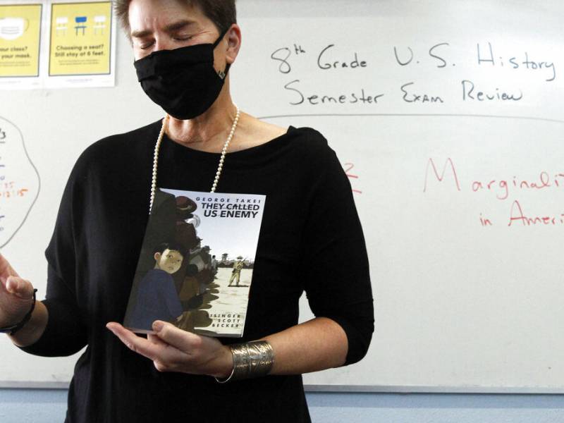 Teacher holding a book about the internment of Japanese Americans