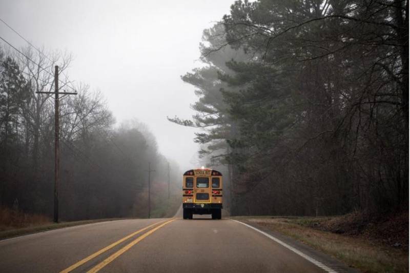 School bus going down a rural road on a foggy day.