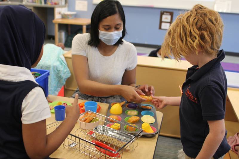 A teacher accepts plastic food items from one of her students.