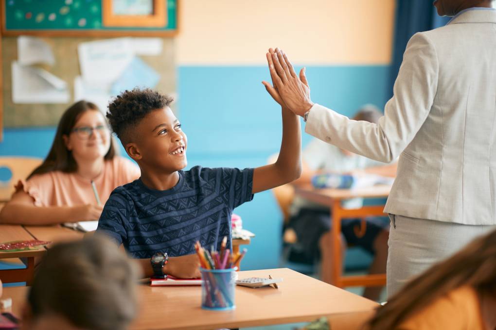 A teacher gives a student a high five