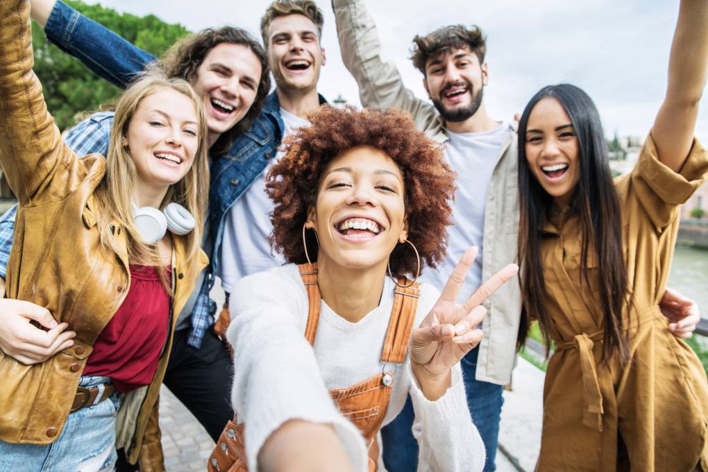 Group of happy young adults taking selfie outside
