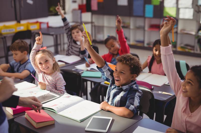 School kids raising their hands in classroom