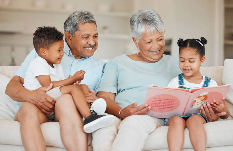 two grandparents reading with two grandchildren