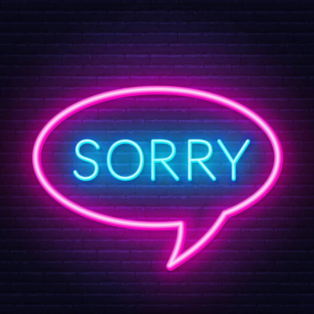 Neon "sorry" sign in speech bubble frame on dark background.