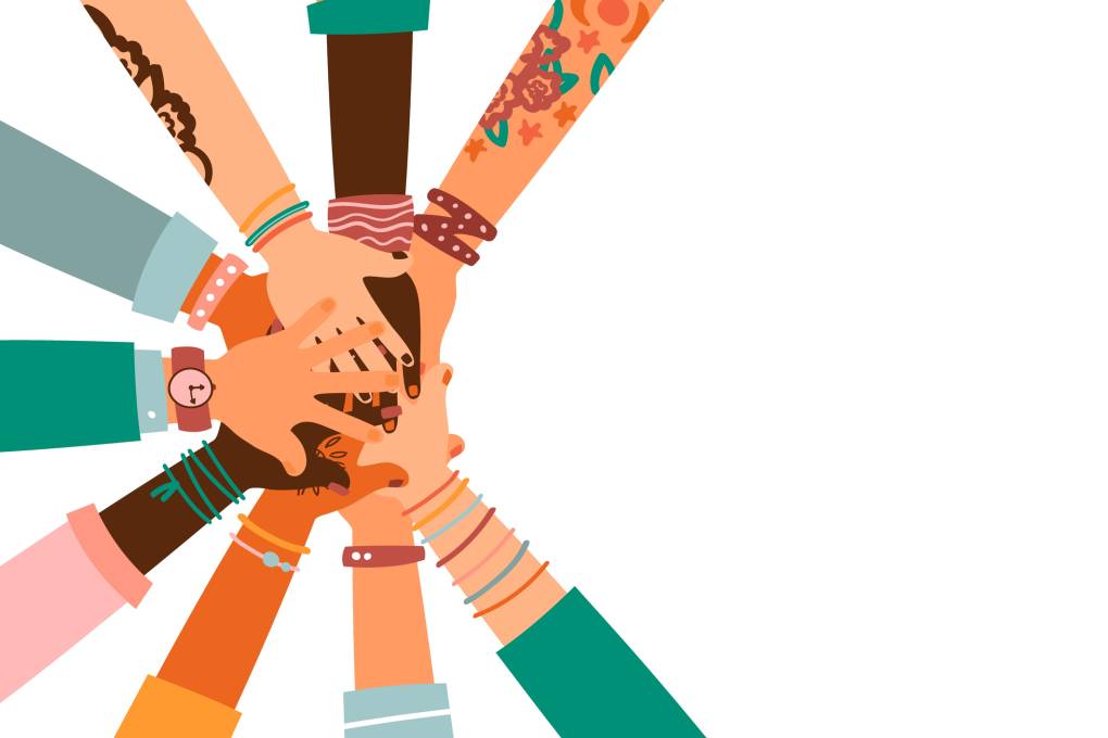 Arms of different races with bracelets and colorful sleeves reaching toward the center and placing hands on top of each other.