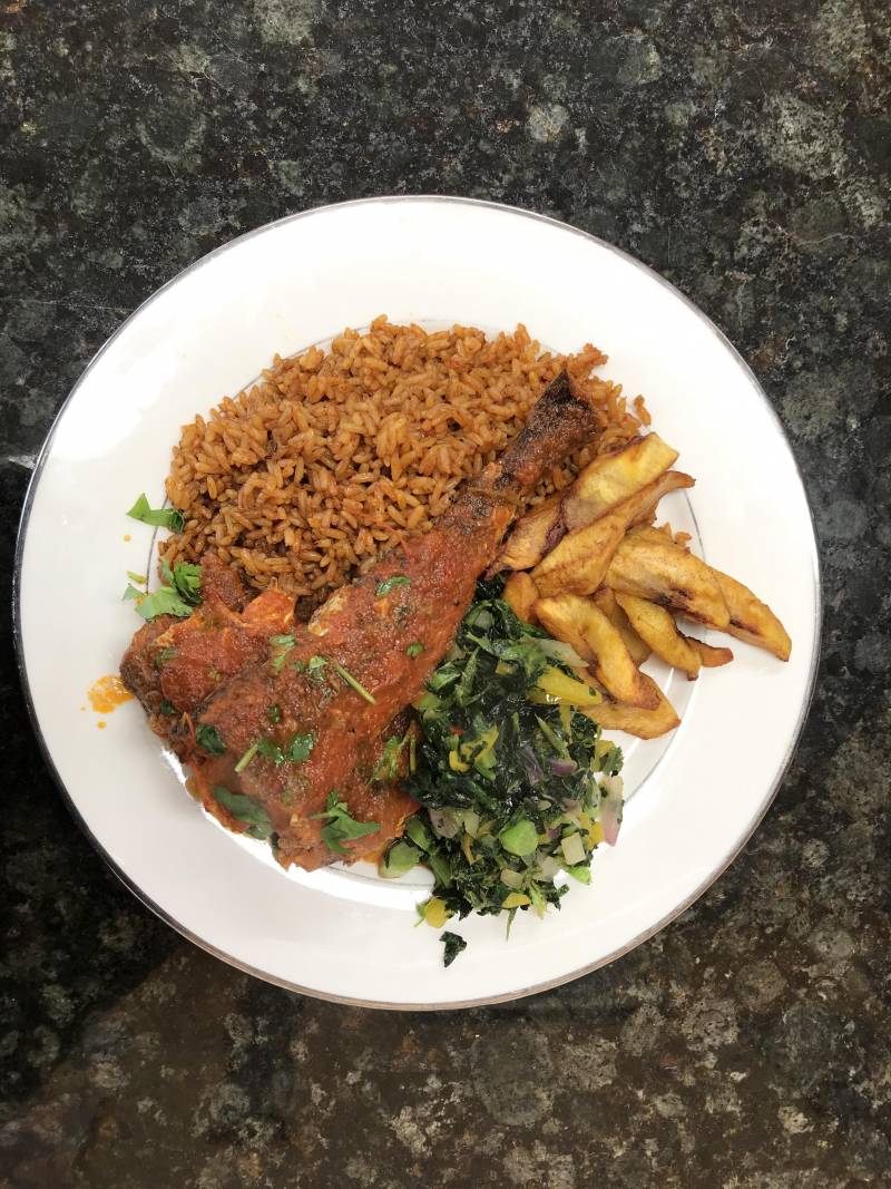 A Jollof rice and plantain plate with tender greens and a fish to top it all of at Ruth's Buka.