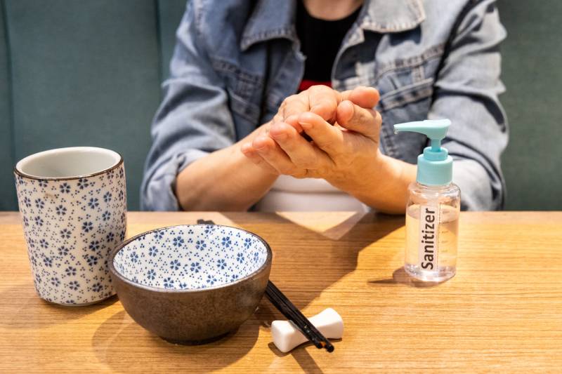 Series of person cleaning hands after spraying with disinfectant sanitizer before meal at dining table
