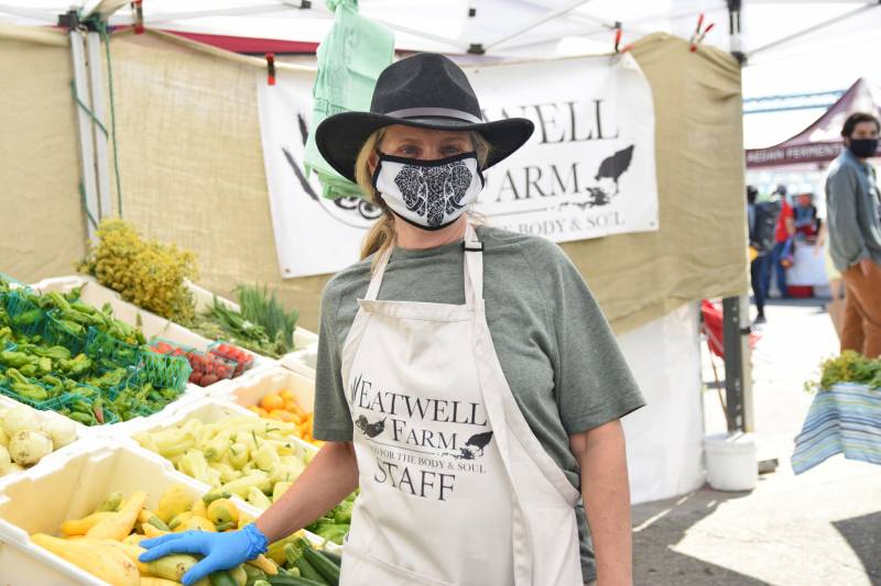 Female farmer wearing a mask at a farmers market