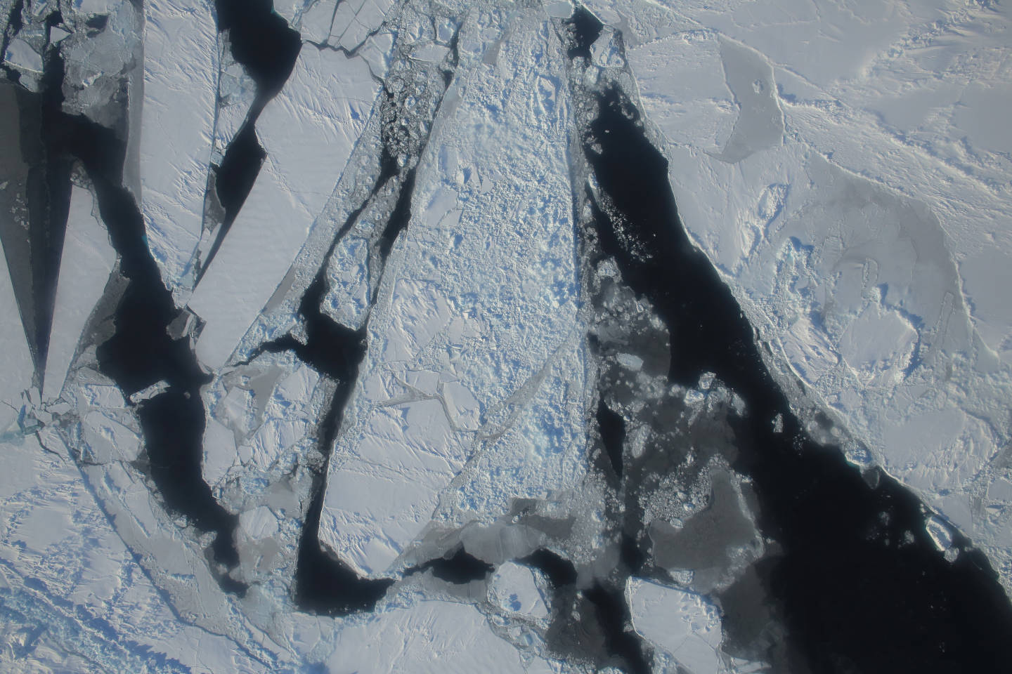 This photograph from a March 27, 2015 NASA IceBridge flight shows a mixture of deformed, snow-covered, first-year sea ice floes, interspersed by open-water leads, brash ice and thin, snow-free nilas and young sea ice over the East Beaufort Sea. Nilas are thin sheets of smooth, level ice less than 10 centimeters (4 inches) thick and appear darkest when thin.  NASA/Operation Ice Bridge.
