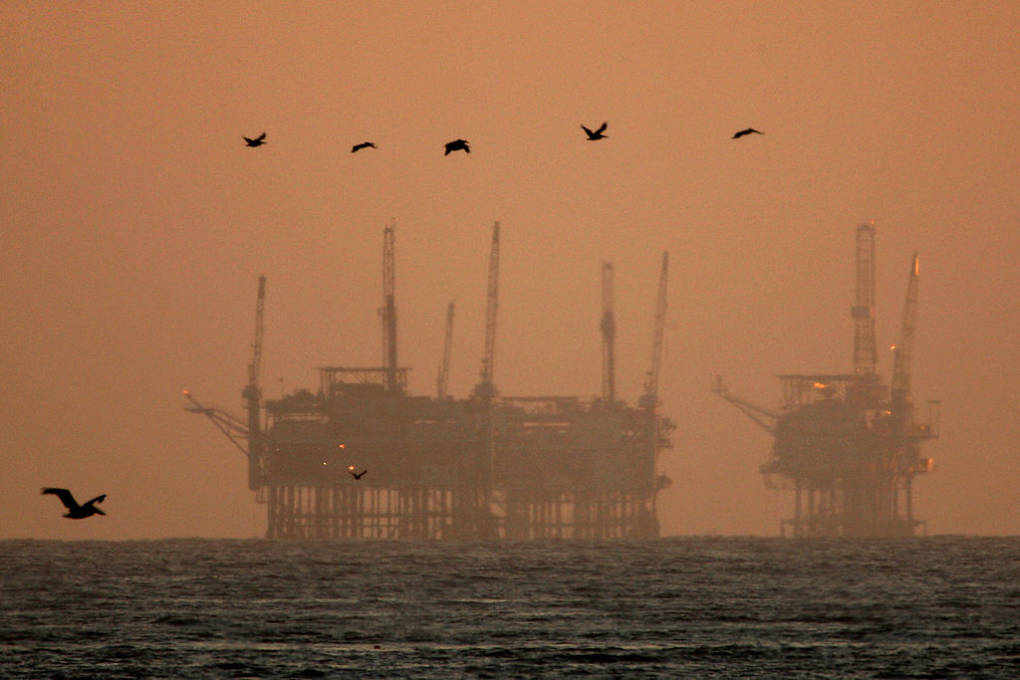 California brown pelicans fly near offshore oil rigs after sunset on July 21, 2009, near Santa Barbara, California.  David McNew/Getty Images