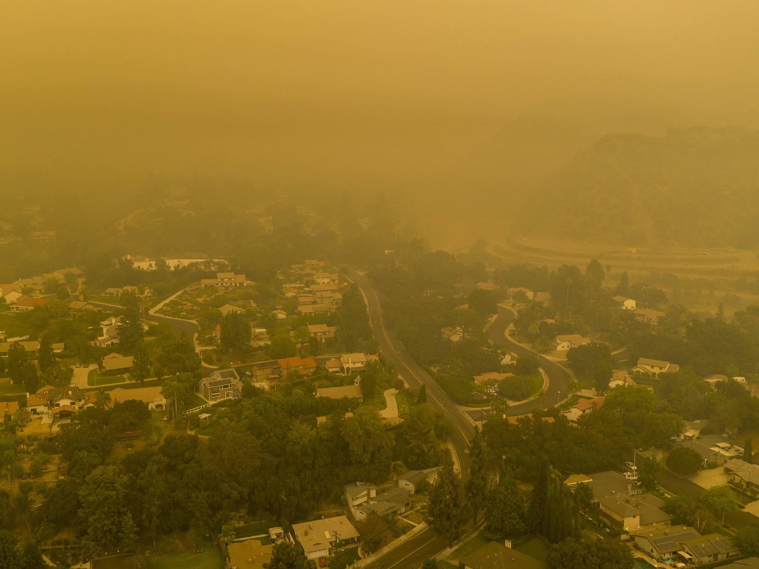 An aerial view shows neighborhoods enshrouded in smoke as the Bobcat Fire advances toward foothill cities and new evacuation order go into effect on September 13, 2020 in Monrovia, California.