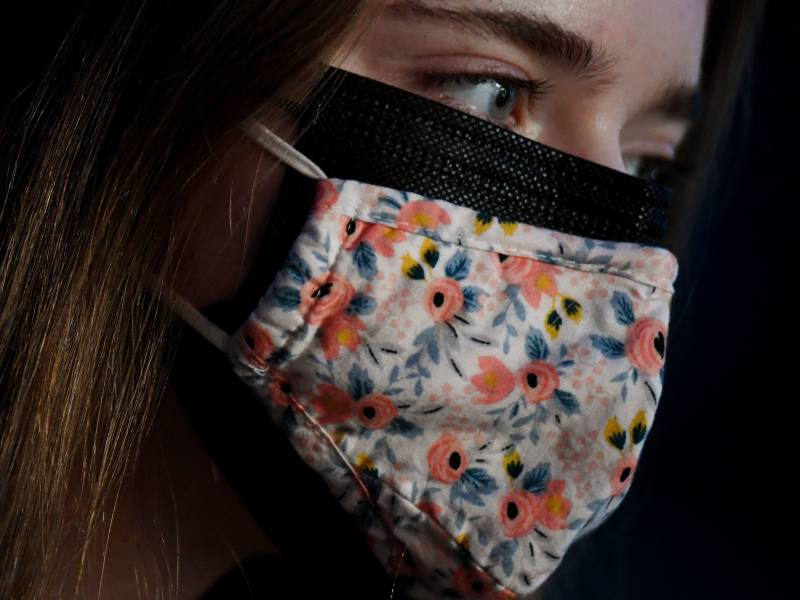 This illustration shows a woman wearing two facemasks, a cloth mask over a surgical mask, in Arlington, Virginia, on February 8, 2021.