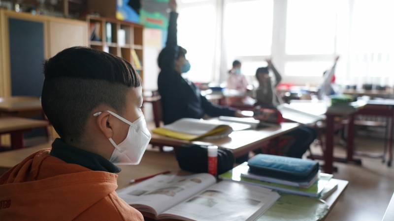 Grade-school students wearing masks sit at desks in a Berlin school.