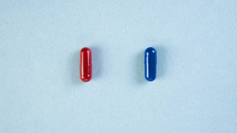 A red pill and a blue pill against a white background.