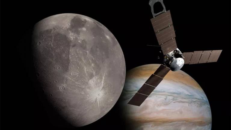 This is an artist's rendering of the spacecraft Juno, the planet Jupiter, and Jupiter's largest moon, Ganymede. Juno looks like a ceiling fan with three flat blades and a silver cylinder in the center. It's in the foreground, with Jupiter behind it, a planet shown in bands of rust, blue-grey and pinkish brown. To the left of the spacecraft is Ganymede, shown as a planet with dark and light grey patches, pockmarked by craters.