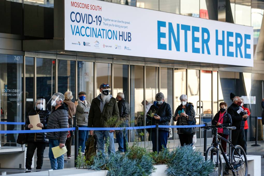People stand in line at the mass vaccination site at San Francisco's Moscone Convention Center. It opened for healthcare workers and people over 65 on February 5, 2021 in San Francisco, California.