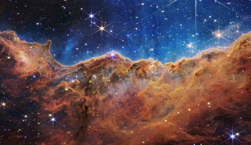What looks much like craggy mountains on a moonlit evening is actually the edge of a nearby, young, star-forming region NGC 3324 in the Carina Nebula. Captured in infrared light by the Near-Infrared Camera (NIRCam) on NASA's James Webb Space Telescope, this image reveals previously obscured areas of star birth.