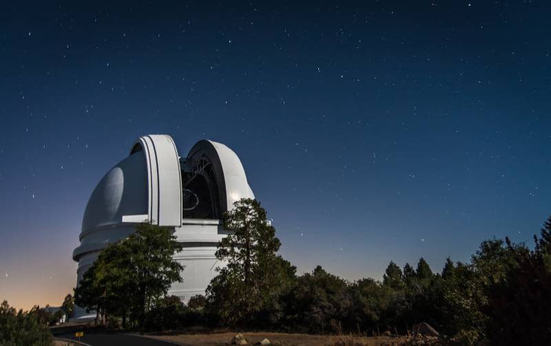 Image shows an observatory with a background of stars and the night sky.