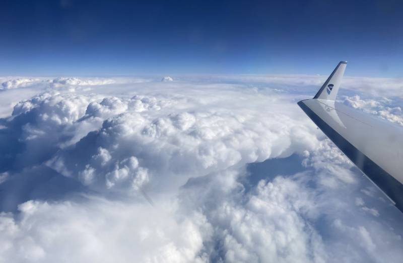 The NOAA Hurricane Hunters plane wing seen above clouds in the clear sky.