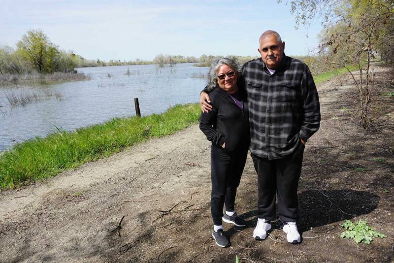 Two people stand in front of a floodplain.