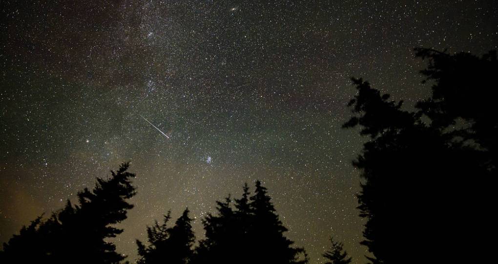 A meteor streaks across a clear, nighttime sky.