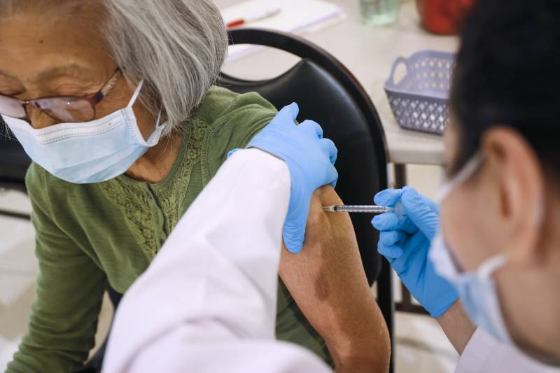 An older Asian woman getting a vaccine shot.
