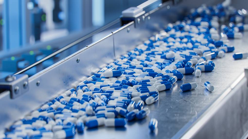Blue capsules on conveyor at a modern pharmaceutical factory.