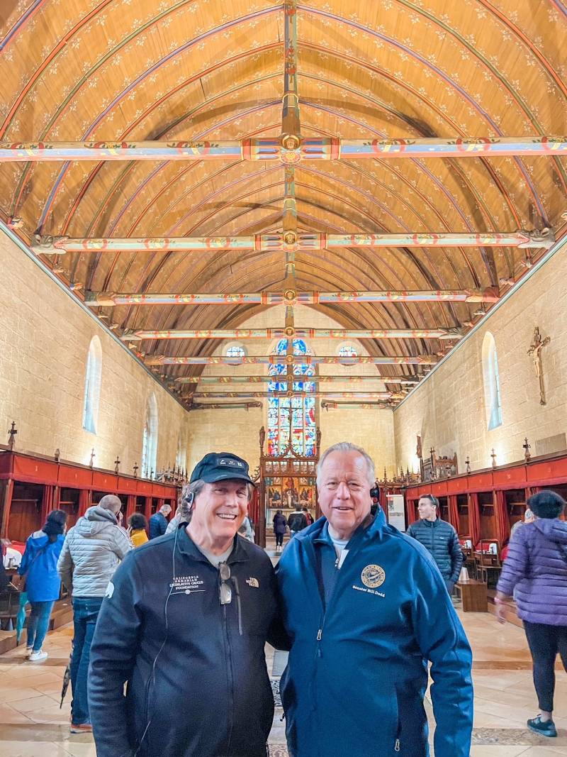 Two men in blue jackets stand in a church.