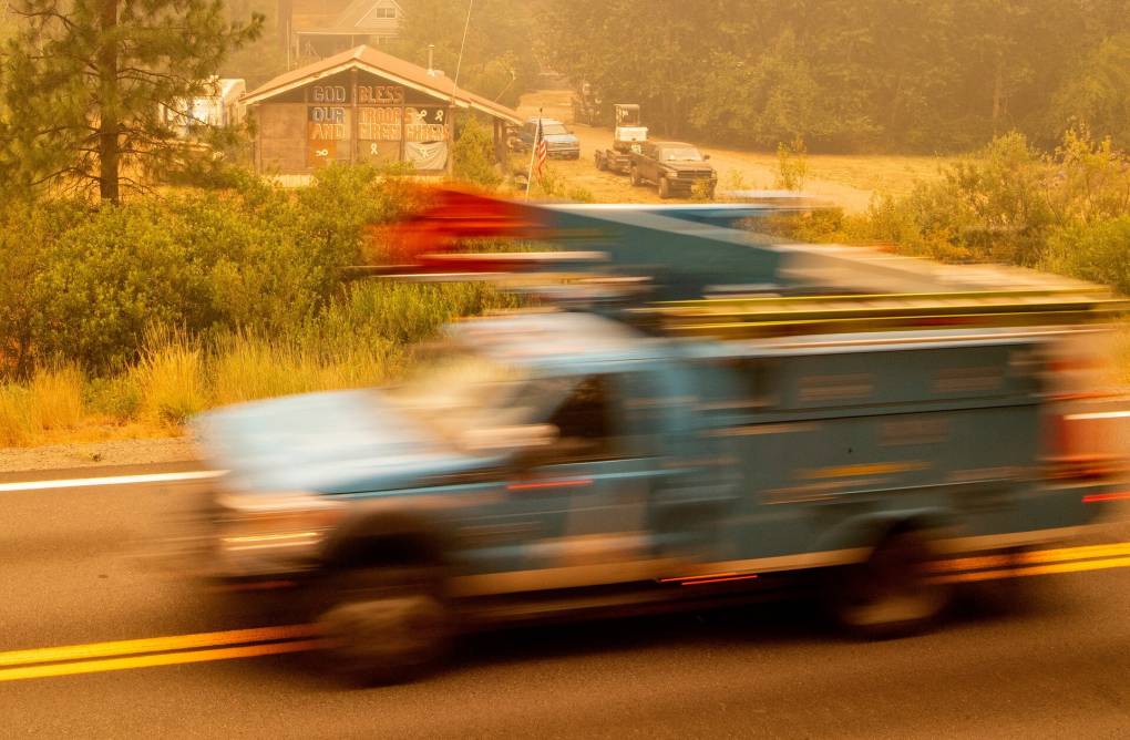 A blurry utility truck drives through a wildfire zone.