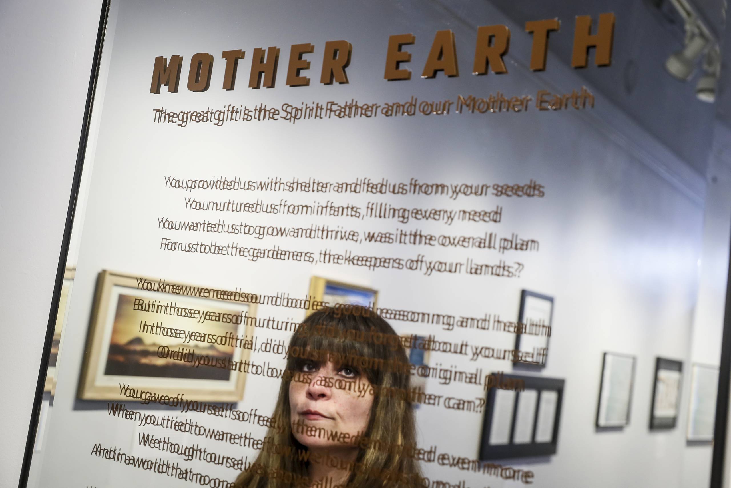 A woman's face is reflected in a mirror with brown writing.