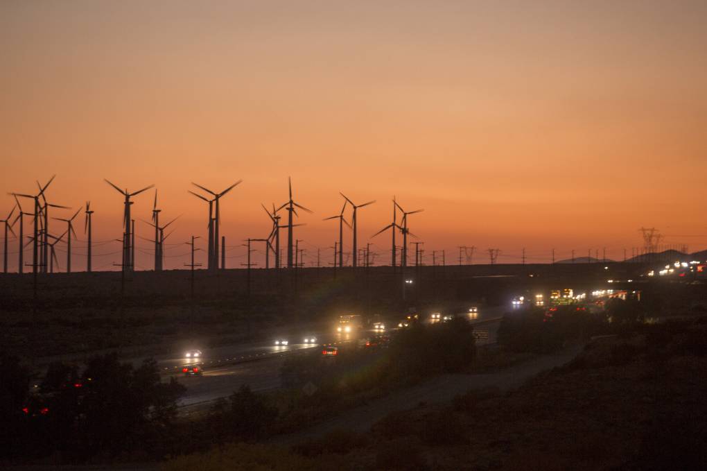 Windmills are seen on a backdrop of orange skies.