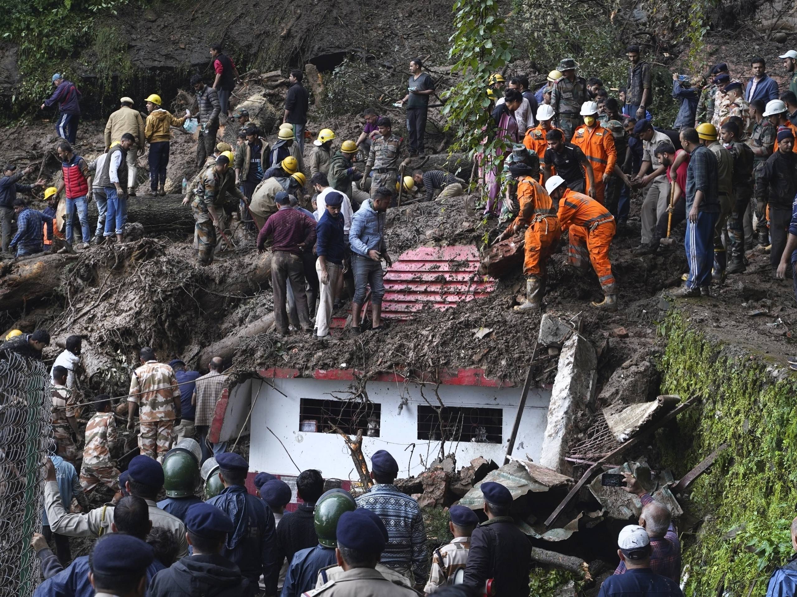 Rescuers remove mud and debris as they search for people feared trapped after a landslide near a temple on the outskirts of Shimla, Himachal Pradesh state, Aug. 14, 2023.