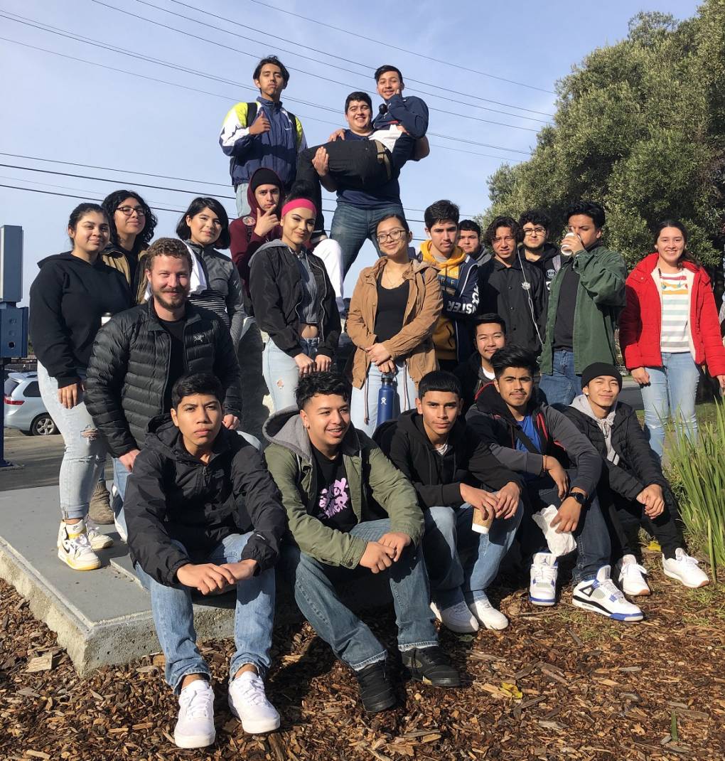 A group of about 20 students from Richmond High School pose for a photo at an outdoor location. Some are seated while some are standing.