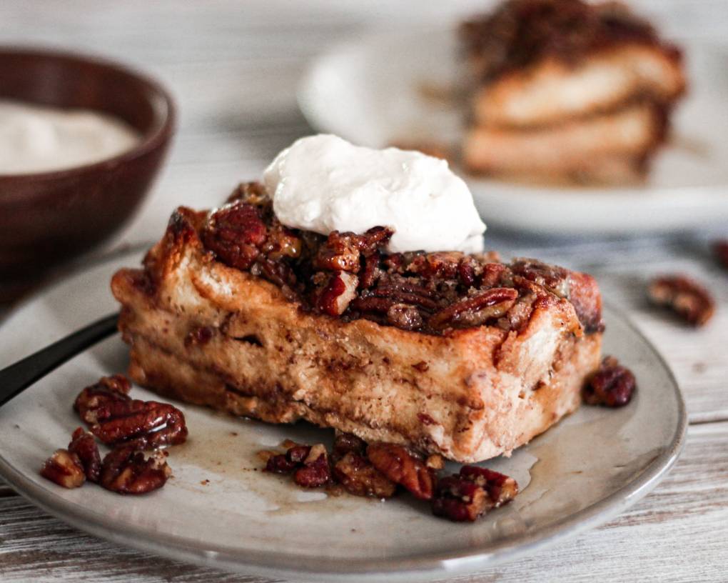 Slice of French toast casserole with whipped cream and pecans