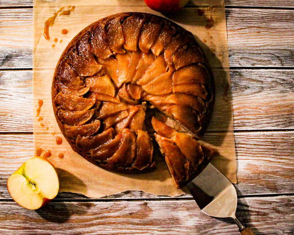 A baked apple cake with spatula removing a slice