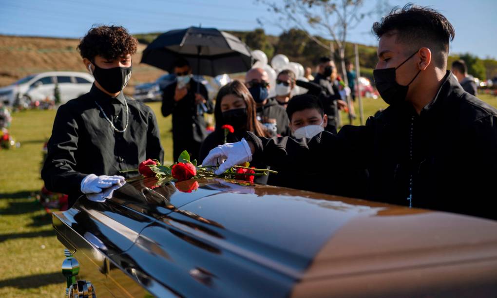 Youth gather around the coffin and place roses on top of it.